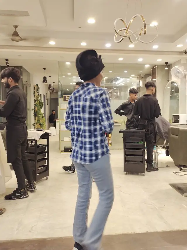 The salon floor: stylists working at mirrored stations with a ring-light chandelier overhead.